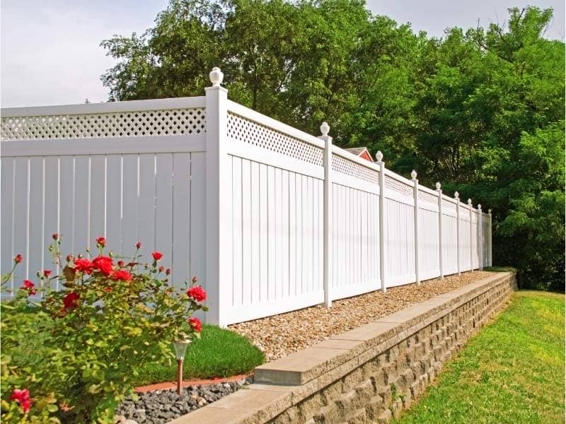 Straight white vinyl fence installed along a residential property boundary showing accurate alignment and clean landscaping from proper survey-based layout