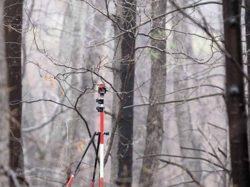 Boundary survey in Alabaster Alabama using surveying equipment on a wooded property.